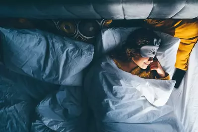 woman in bed wearing sleeping mask