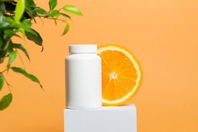 bottle of vitamin c supplements next to orange slice